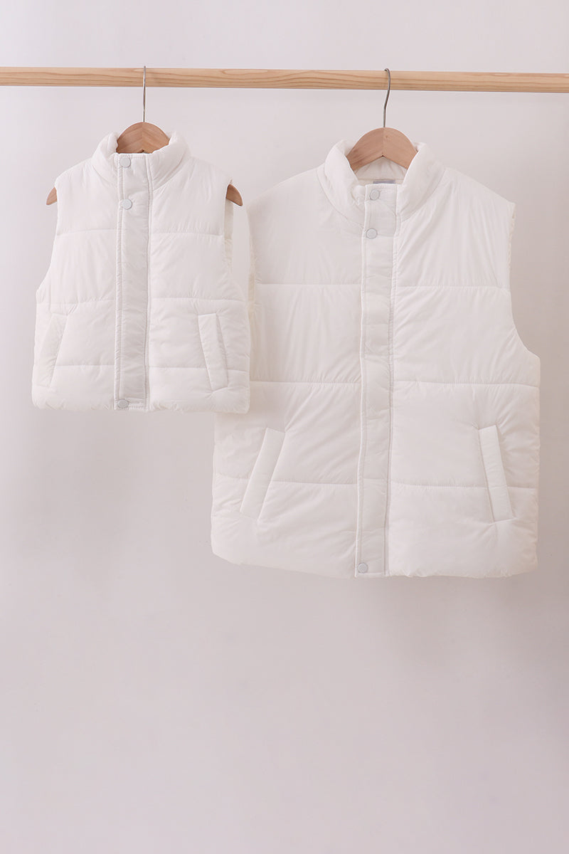 Two white puffer vests hanging on wooden hangers against a white background